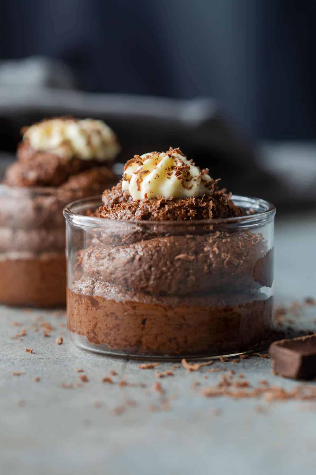 eggless chocolate mousse served in glass jars topped with whipped cream and a sprinkle of grated chocolate