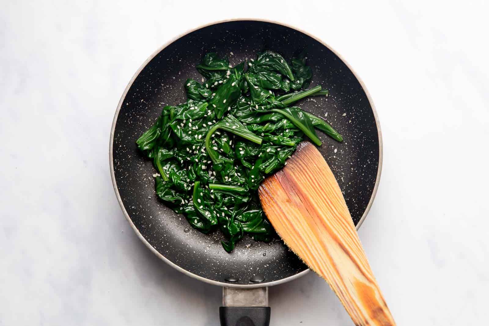 Sauteed Spinach in a pan topped with sesame seeds