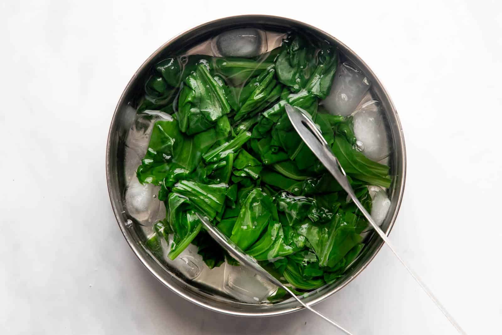 Blanched spinach dunked in ice cold water to stop the cooking process