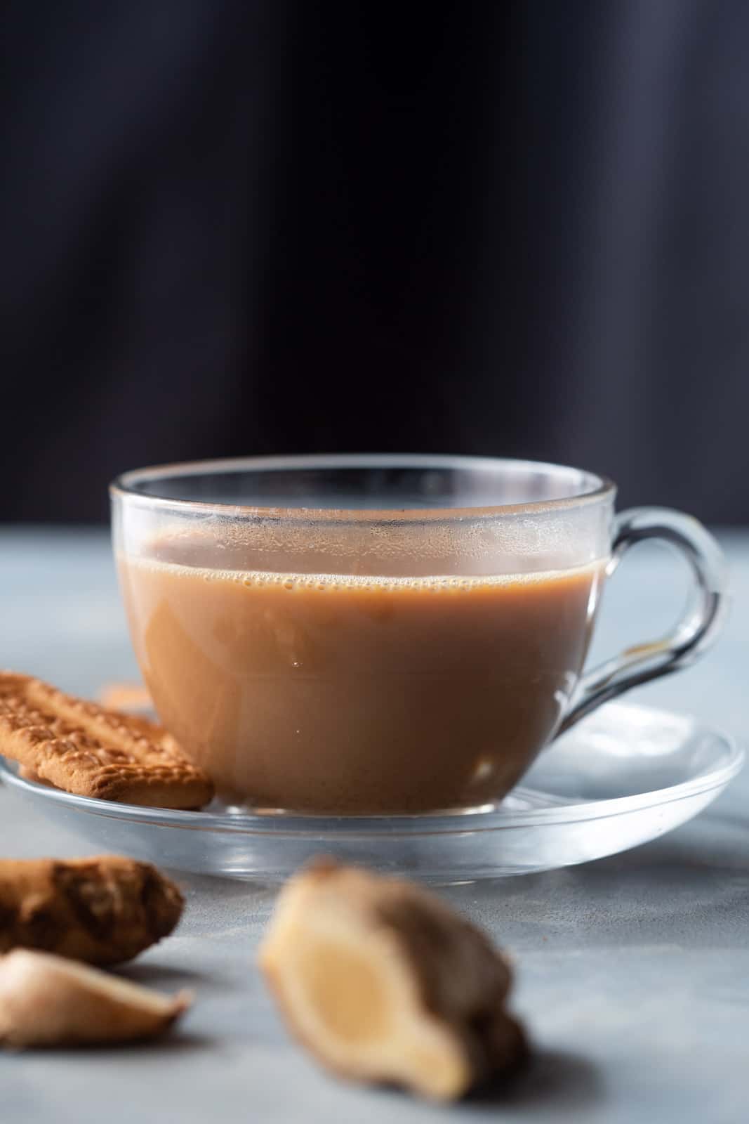 A cup of ginger chai with biscuits on the side