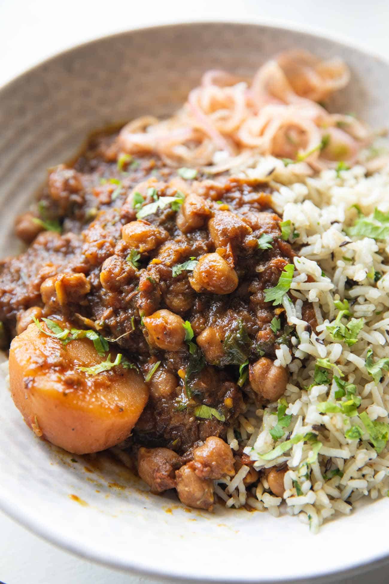 Close up shot of pressure cooker chana masala served in a bowl with rice on the side