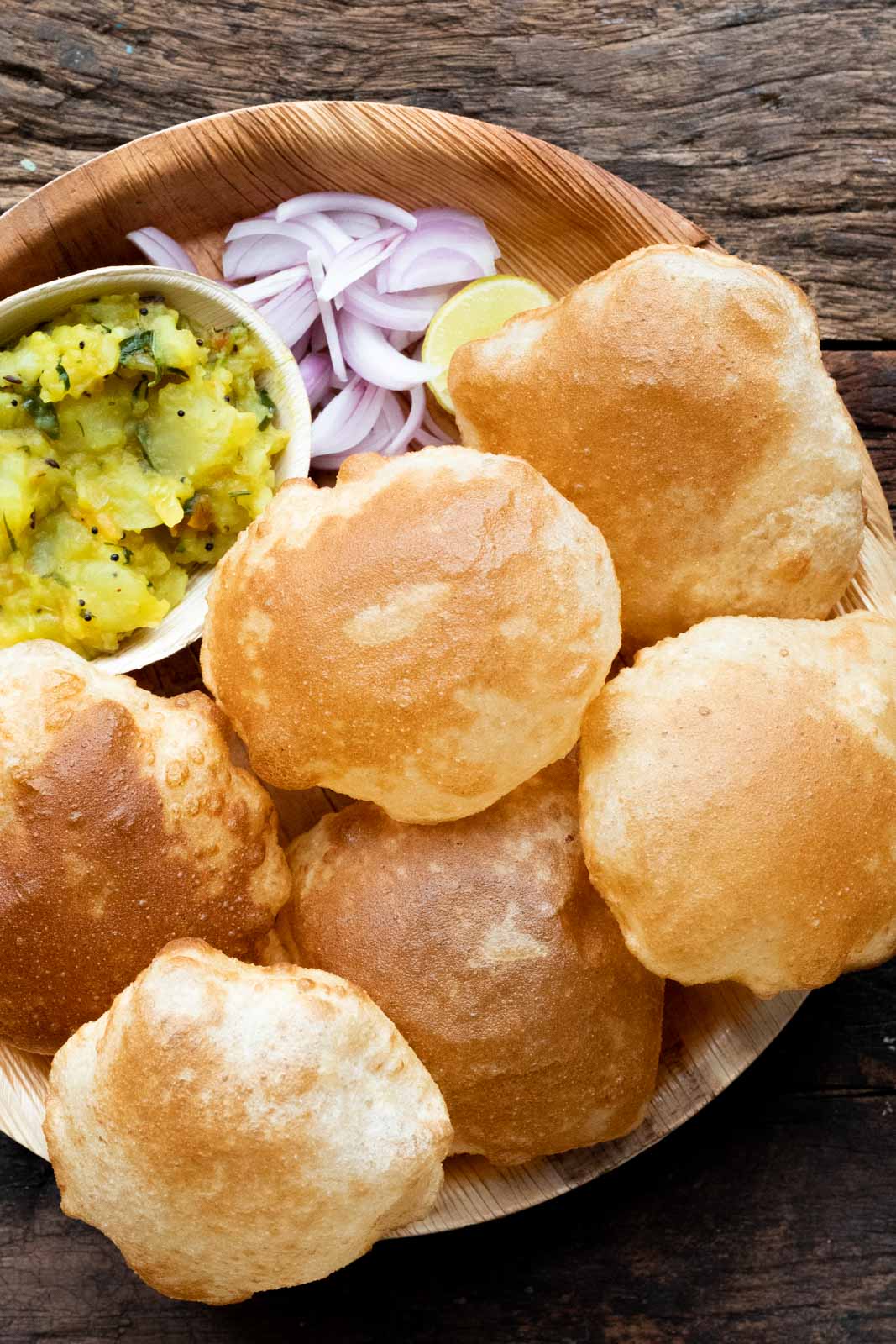 Pooris served on a plate with aloo bhaji, onions