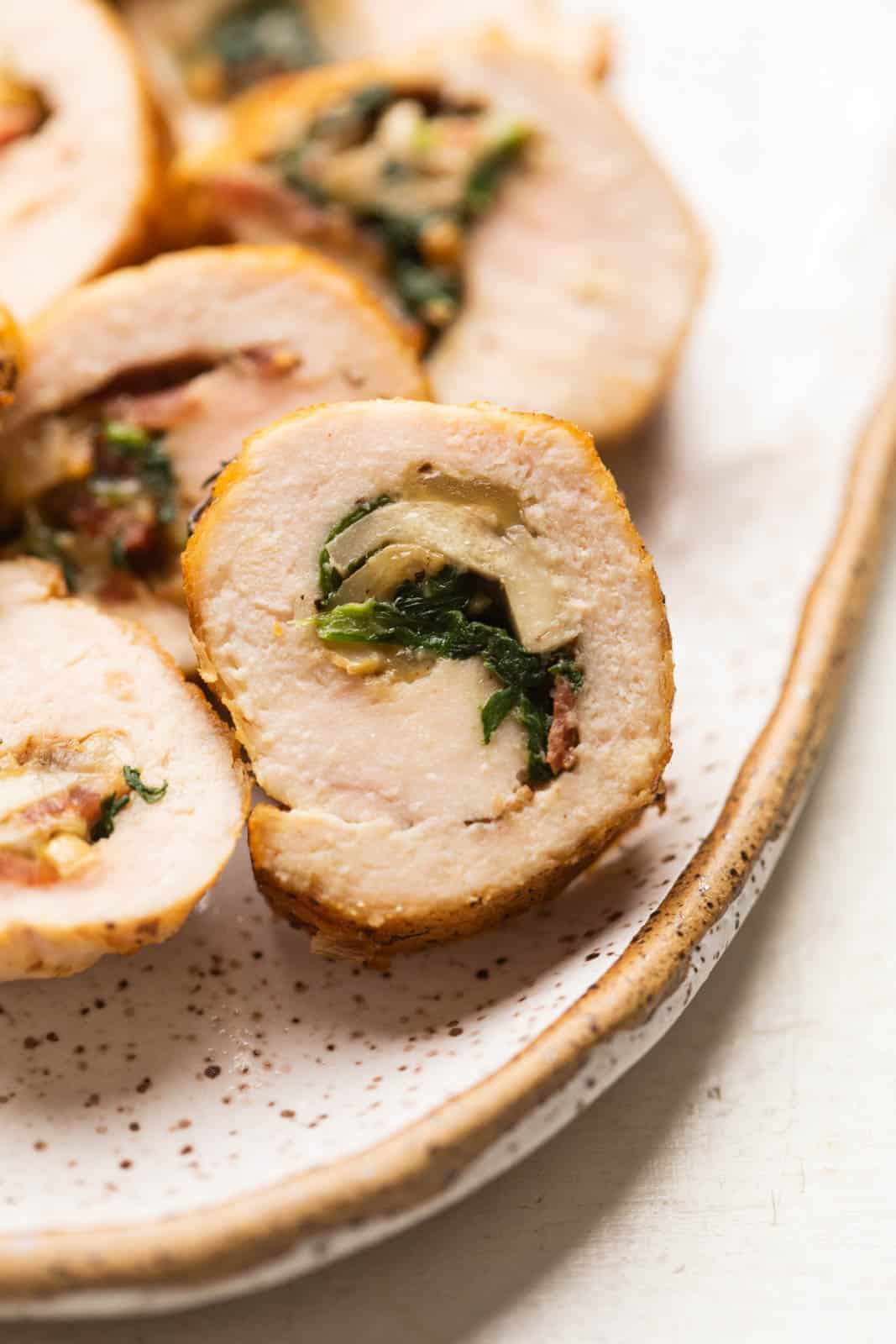 Closeup of a slice of chicken roulade to show the layers and the stuffing inside