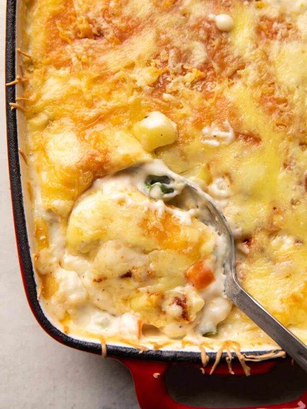 Closeup of a picture showing a spoon serving veg au gratin out of the casserole dish