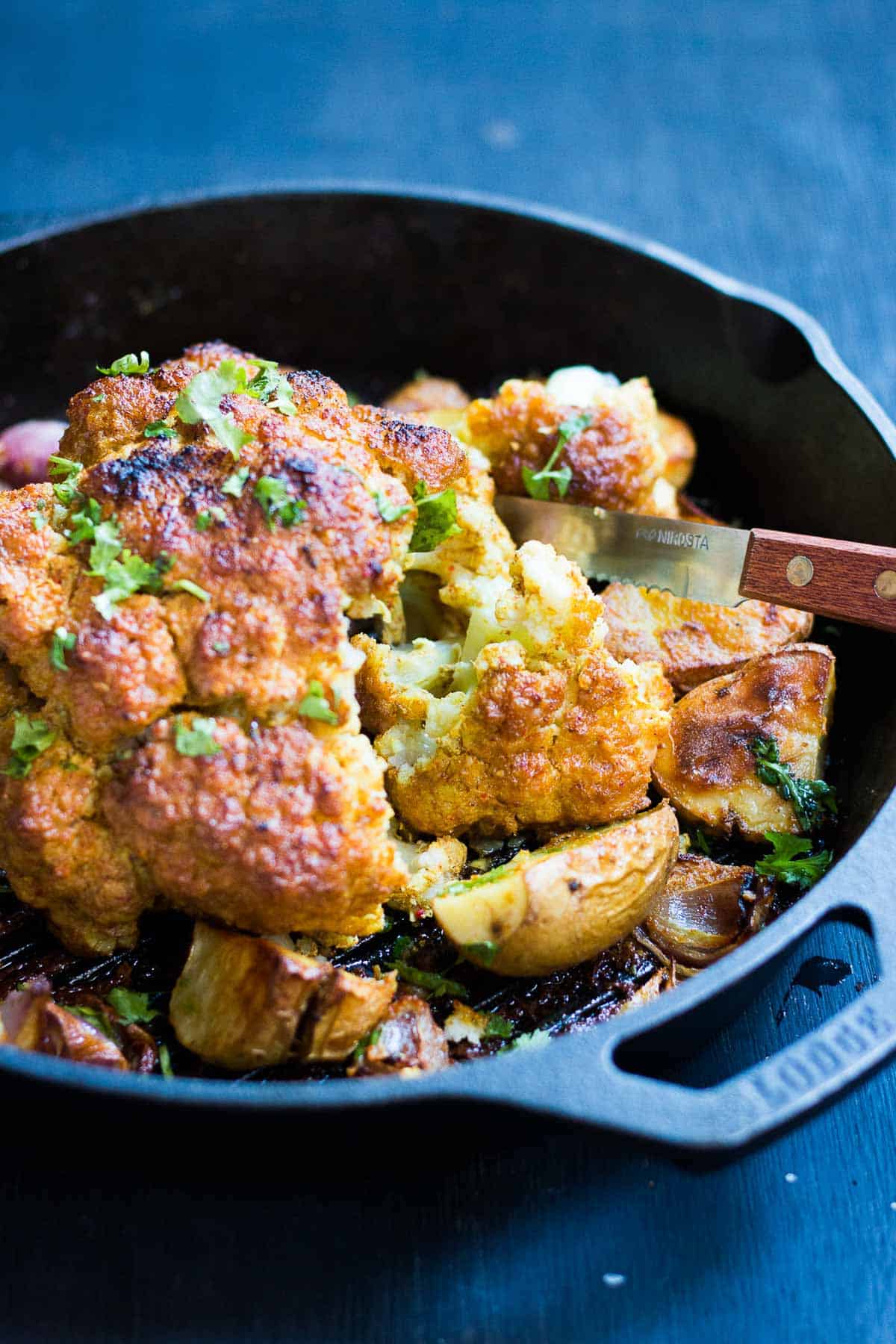 The tandoori cauliflower served with onions and potatoes in a skillet.