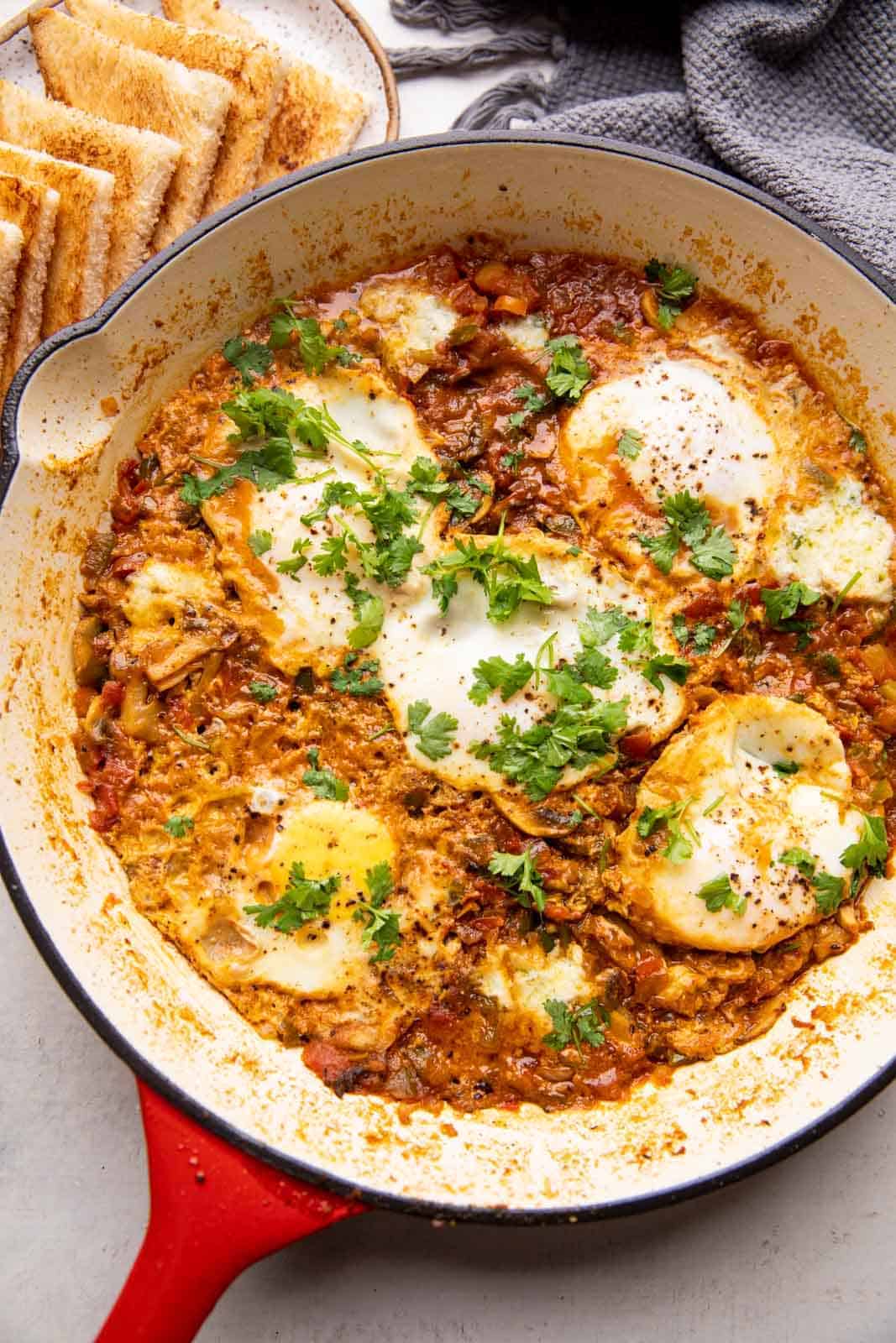 Masala shakshuka in a large pan served with toasted bread