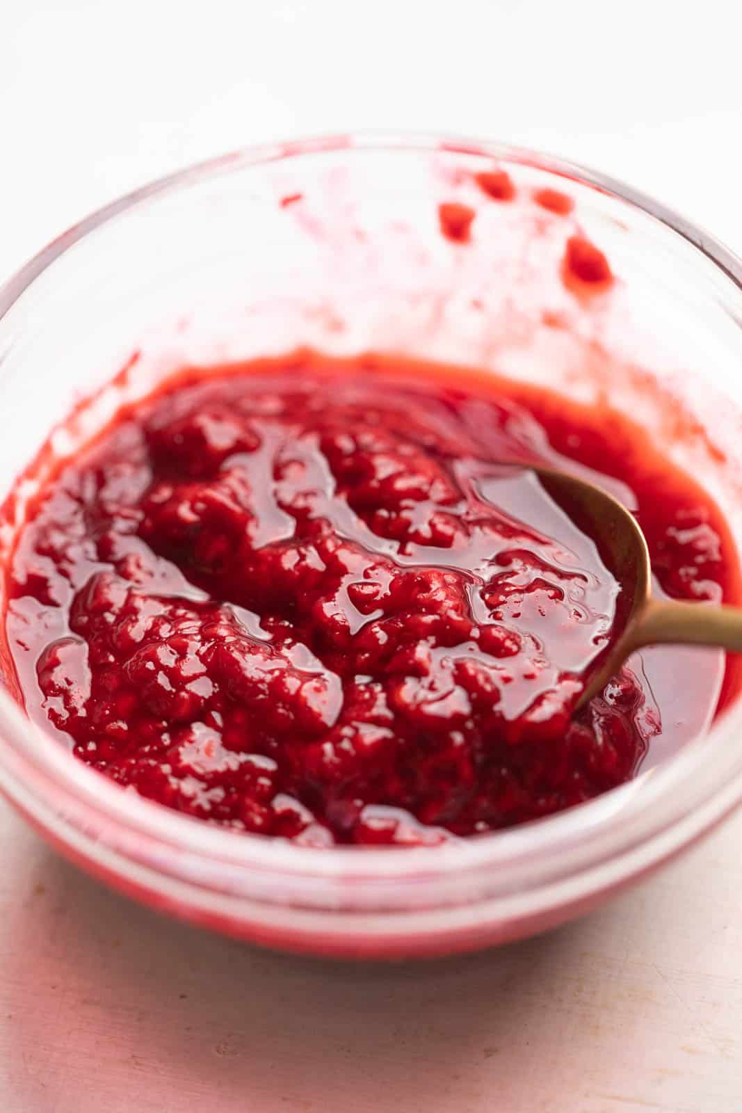 Raspberry coulis in a bowl with a spoon