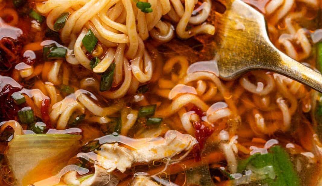Closeup of noodles twirled around a fork in a bowl of chicken thukpa soup