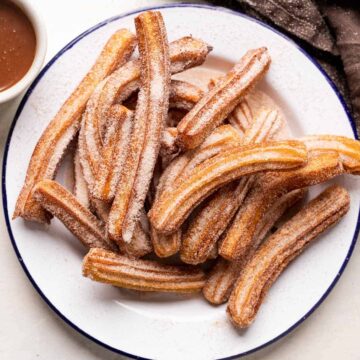 Churros piled on a plate and served with chocolate sauce