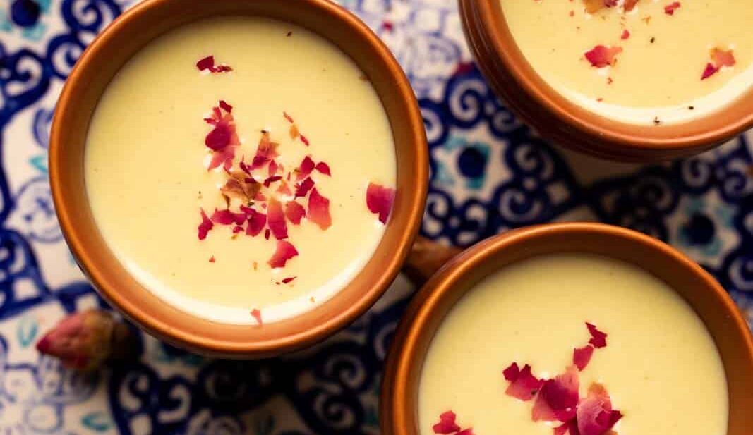 Thandai served in three mud glasses served on a colourful blue plate with rose petals on top
