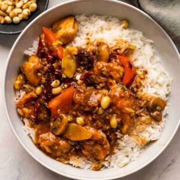 Kung Pao Chicken served over rice in a bowl with peanuts on the side