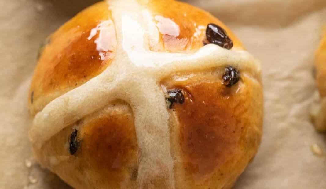 Closeup of one hot cross bun to show how beautifully glazed they are