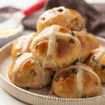 A pile of hot cross buns stacked on a black and white plate