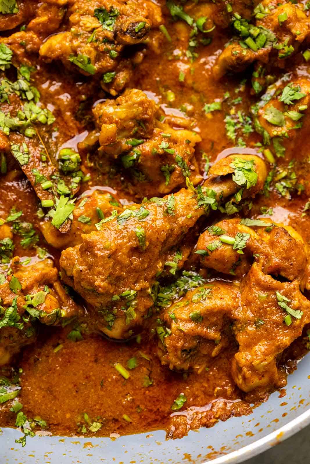 Close up of chicken curry to show texture of the gravy and succulent, juicy pieces of chicken