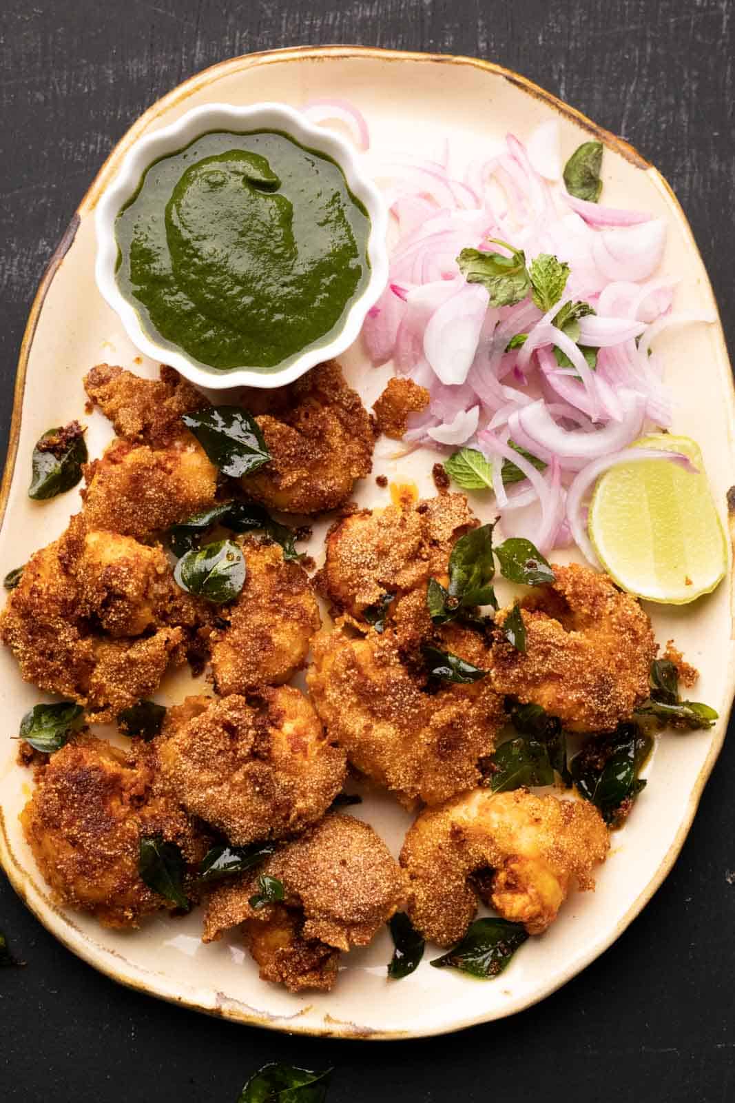 Prawn Rava Fry served on a beige platter with chutney and sliced onions on the side