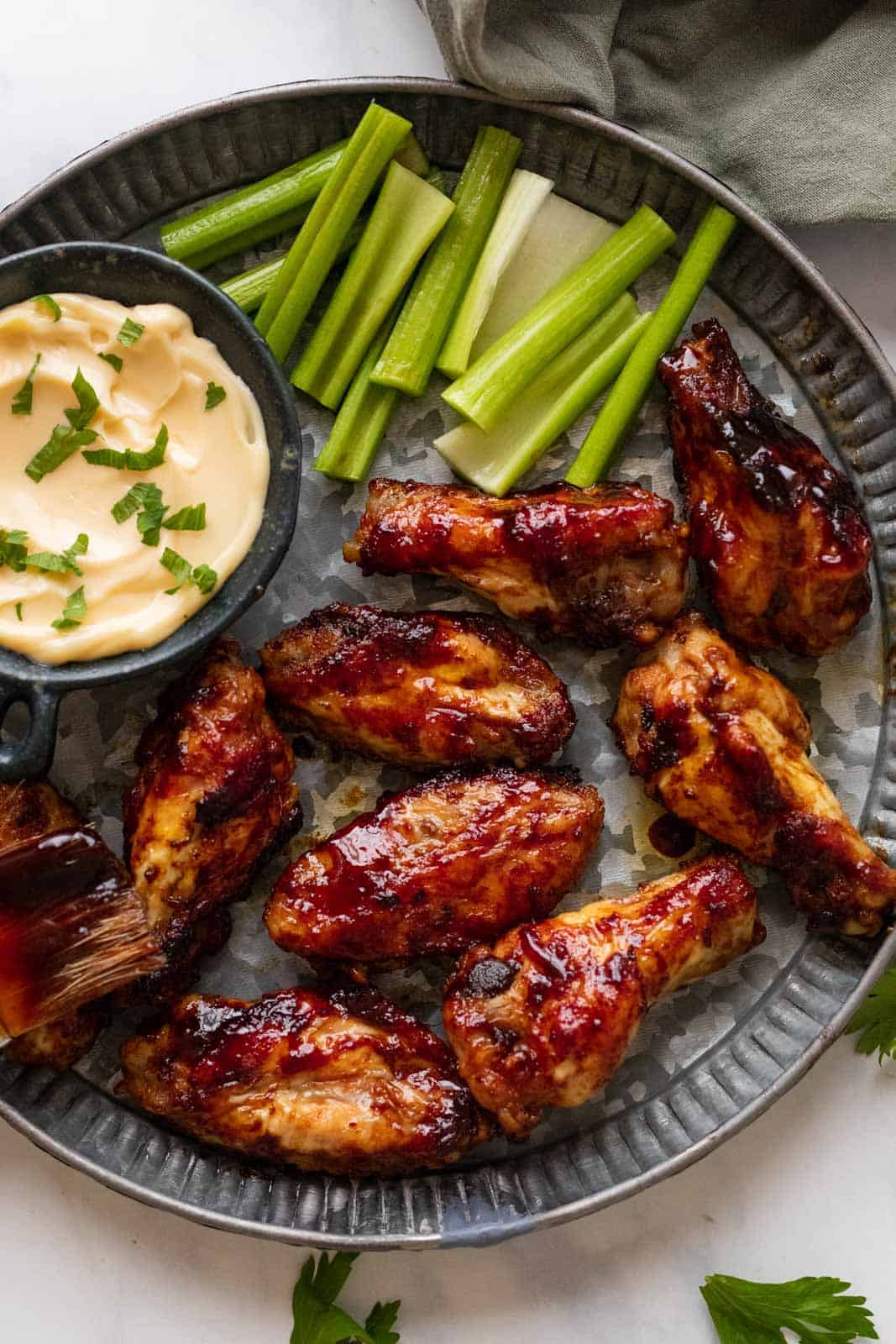 Spicy BBQ Chicken Wings on a hammered silver plate with aioli and celery on the side