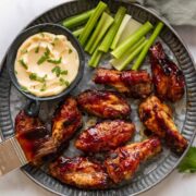 Spicy BBQ Yellow Wings on a hammered silver plate with aioli and celery on the side