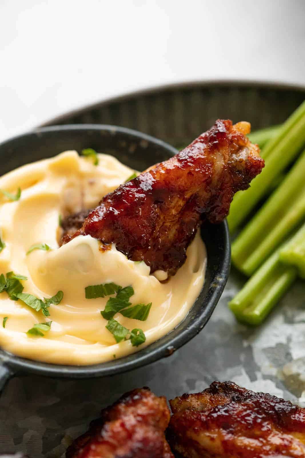 A single chicken wing dipped into aioli
