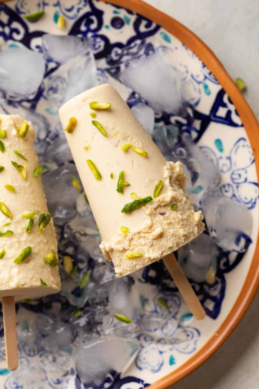 Badam Pista Kulfi served on a plate with some ice to keep it frozen