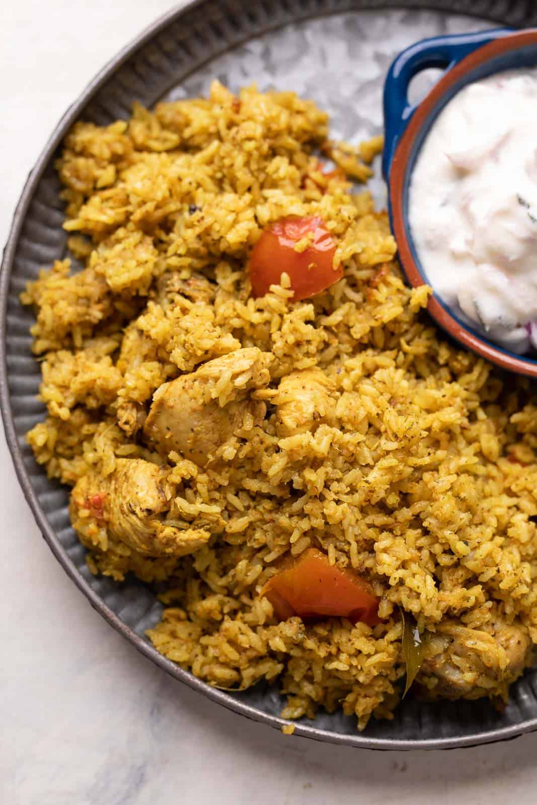 Chicken Pulao served on a grey plate with raita