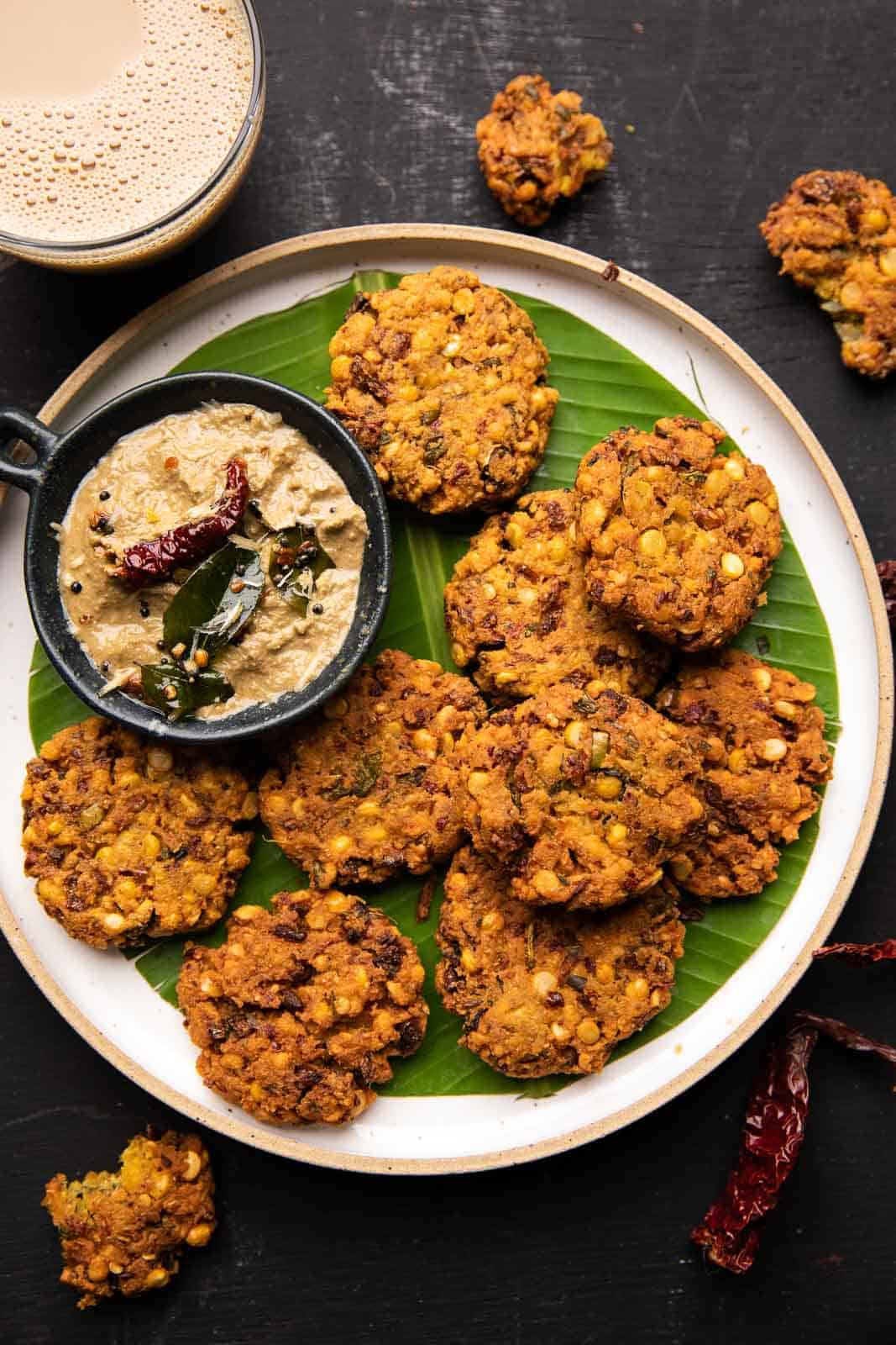 Crispy masala vadas served on a banana leaf lined white plate with coconut chutney on the side