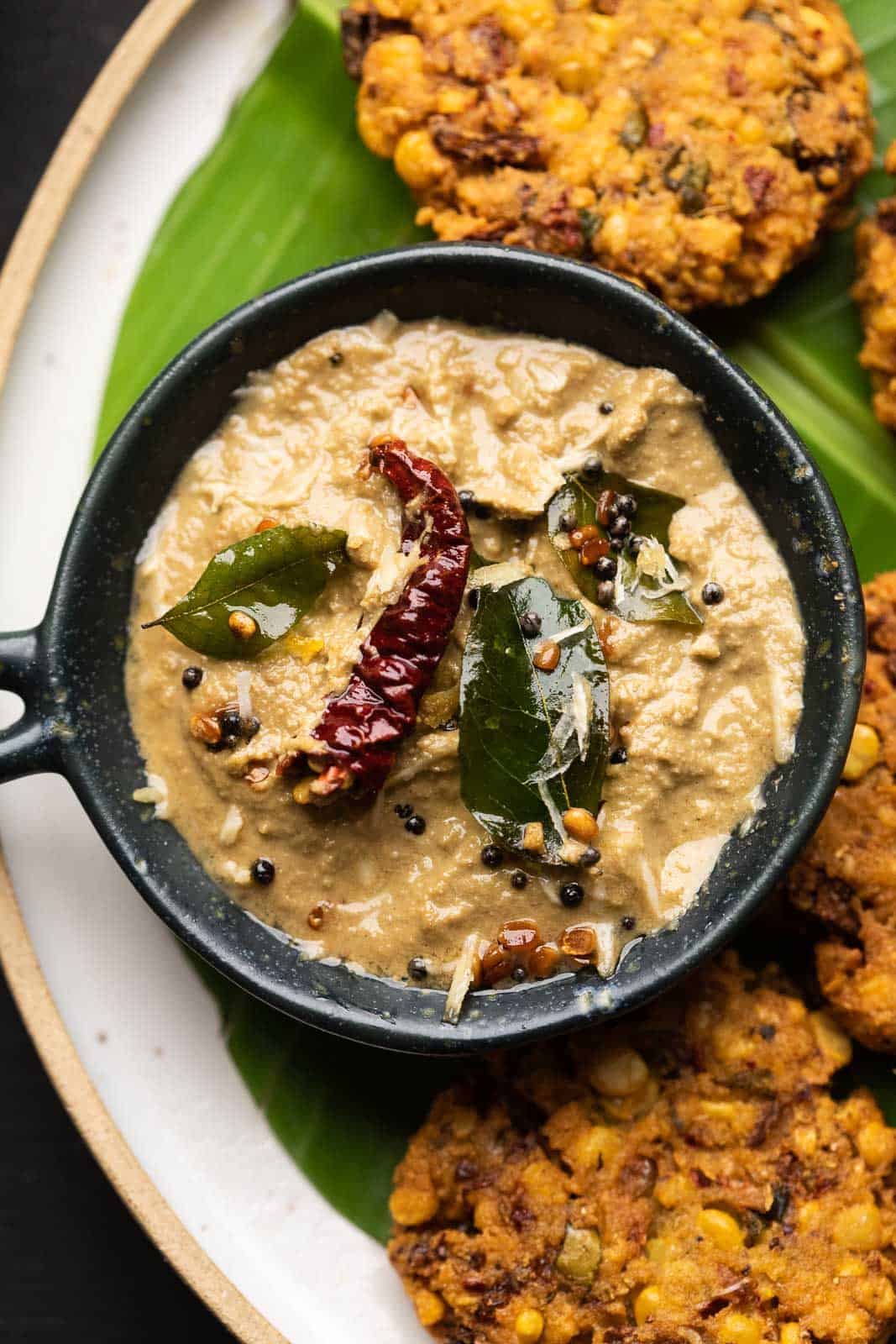 Closeup of the coconut chutney served in a dark grey bowl with the masala vadas