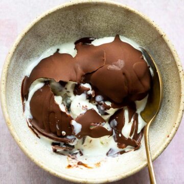 Cracked chocolate magic shell with vanilla ice cream to show the texture in a brown bowl