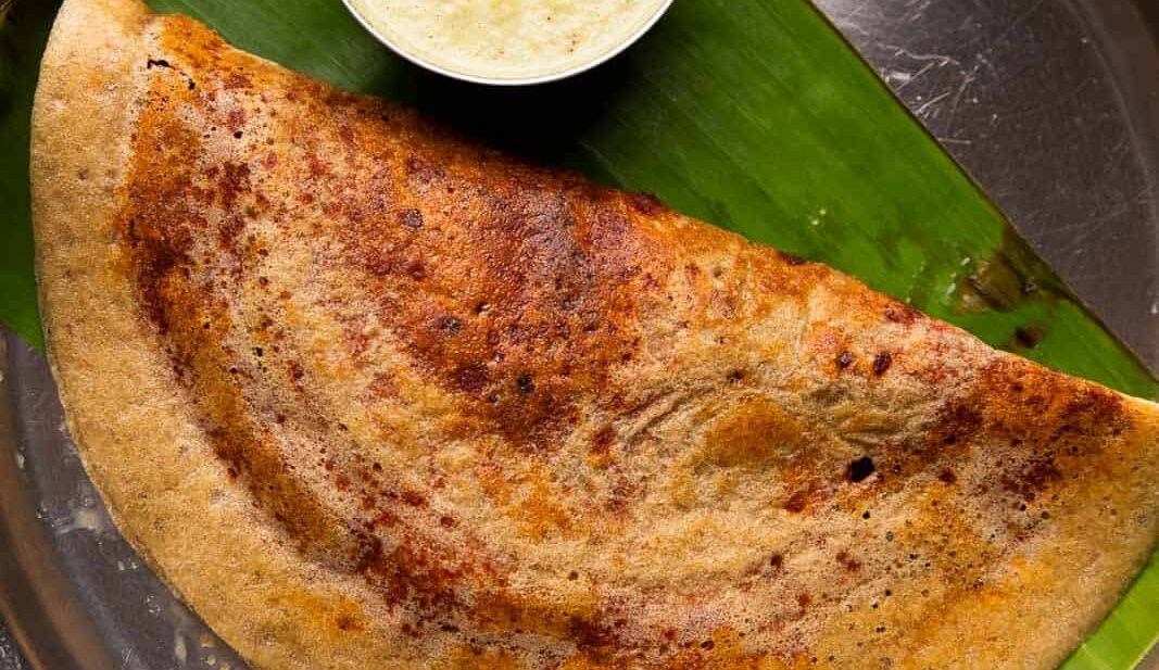 Millet mysore masala dosa served on a steel plate with chutney and filter coffee