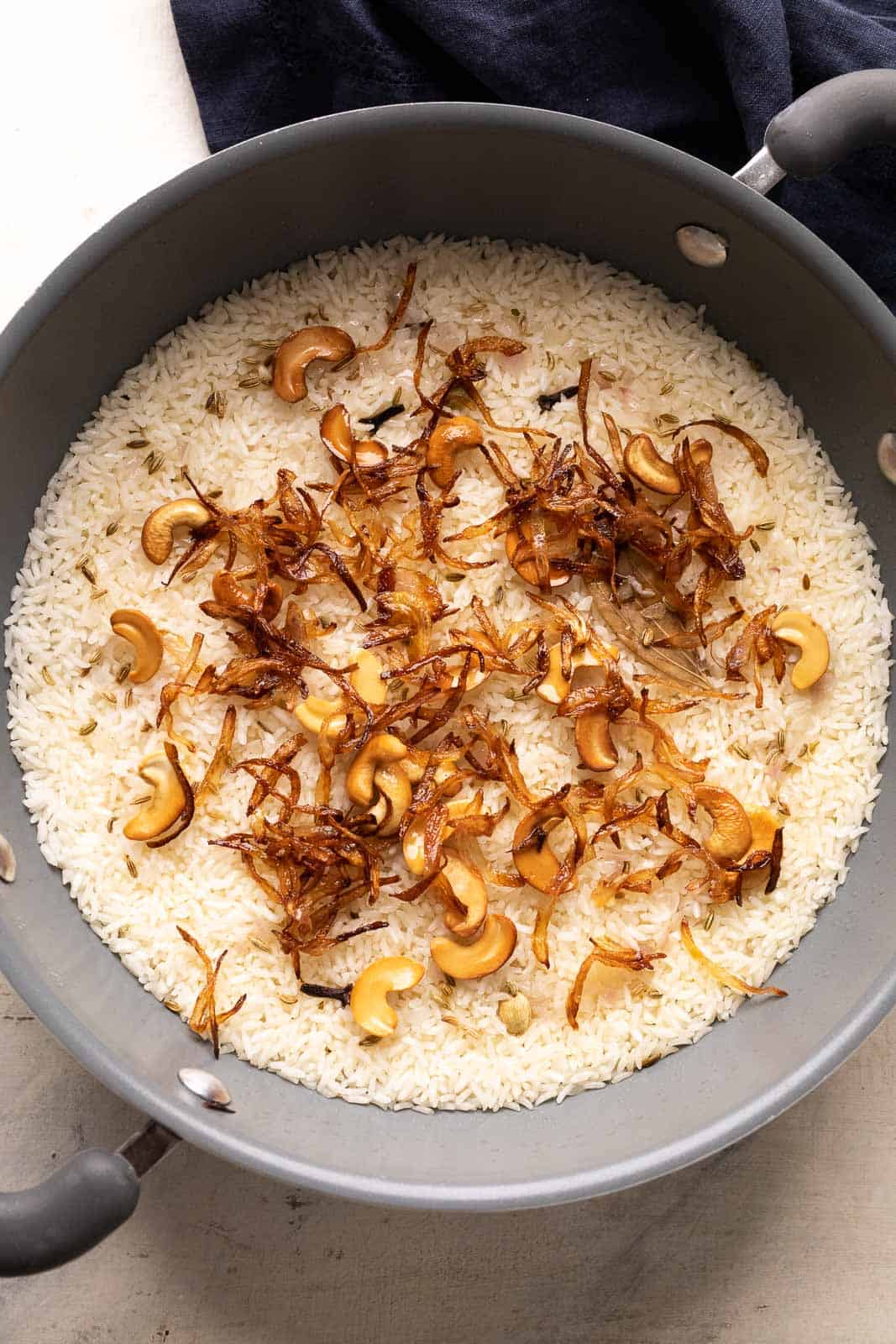 Ghee Rice pictured in the pot that it was made in topped with fried onions and fried cashews