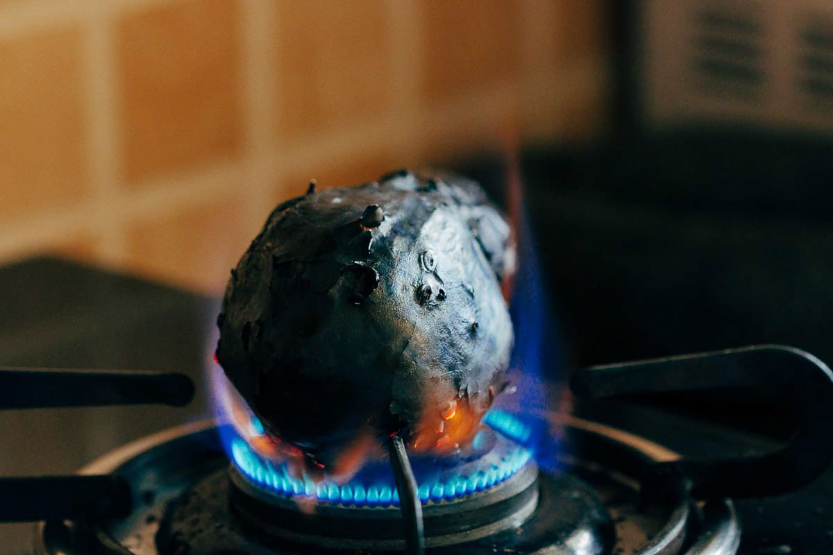 Roasting baingan on an open flame for baingan bharta.