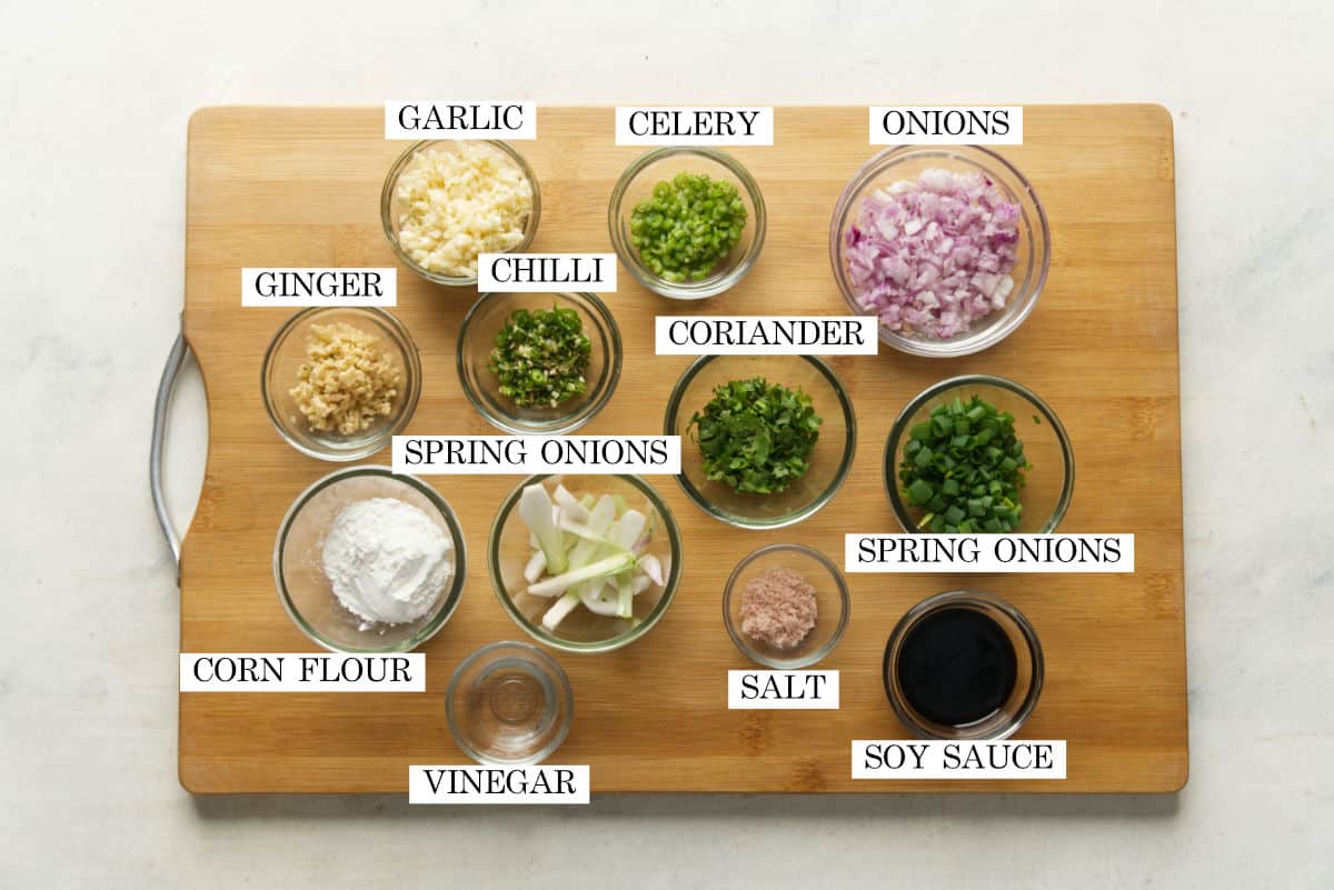 All the ingredients required for manchurian sauce pictured on a wooden chopping board with text to identify them