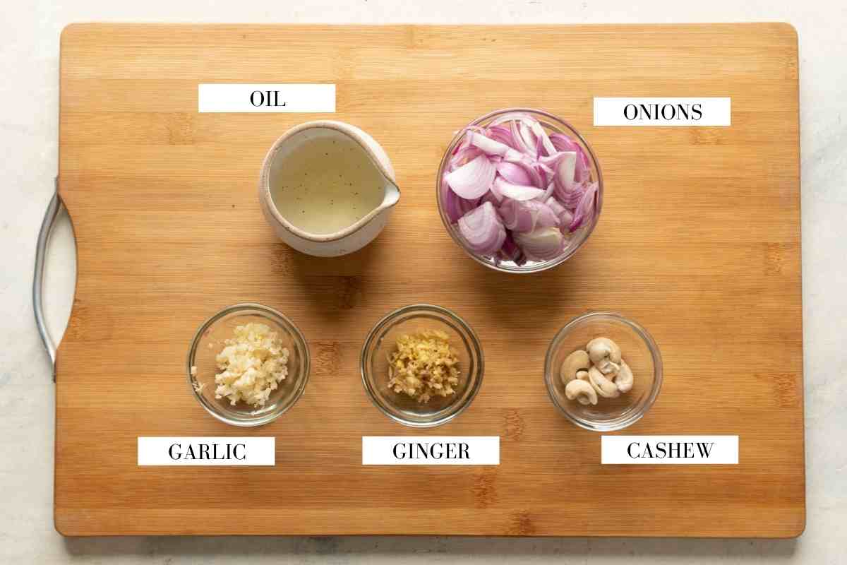 Ingredients for making the onion paste for chicken kali mirch on a brown board with text to identify them