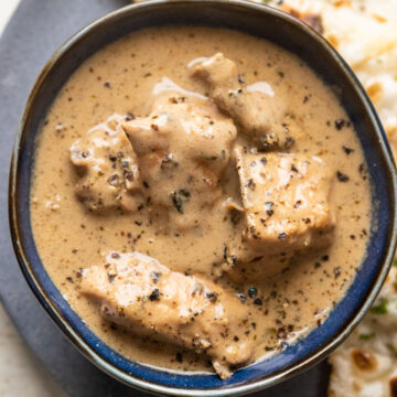 Chicken kali mirch gravy served in a blue bowl with naan on the side