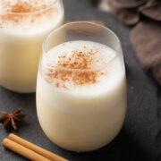 Picture of two glasses of non drunkard eggnog with powdered cinnamon sprinkled on it