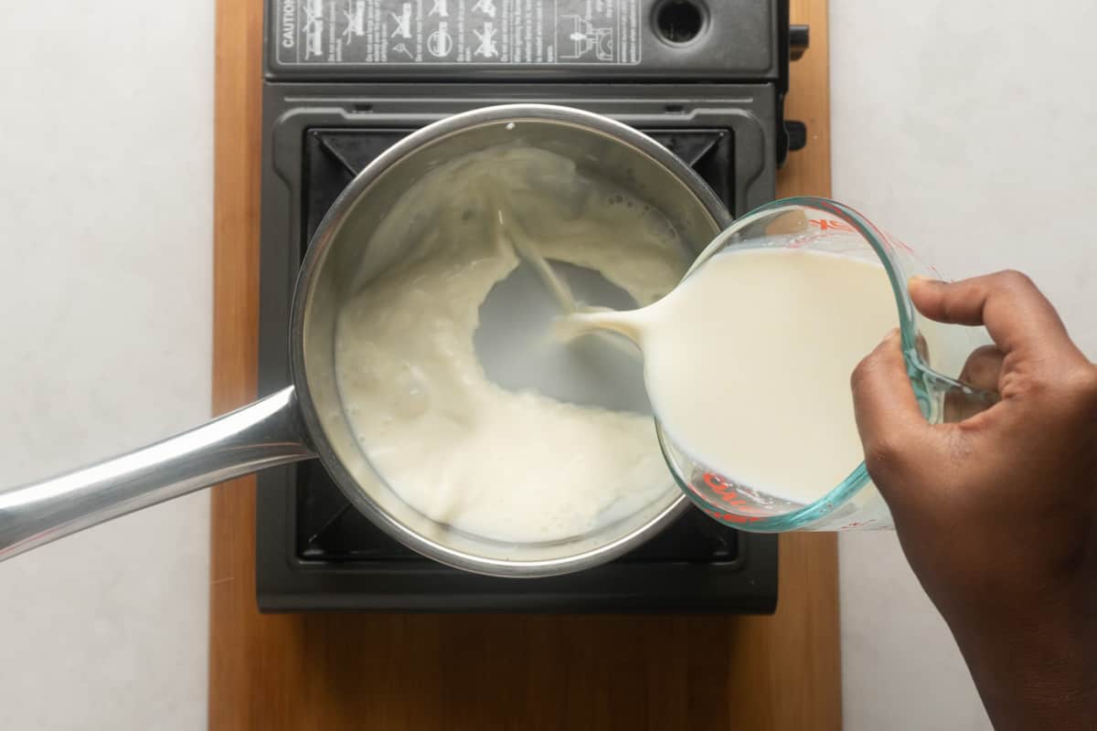 Picture showing milk being poured into a sauce pot to make eggnog