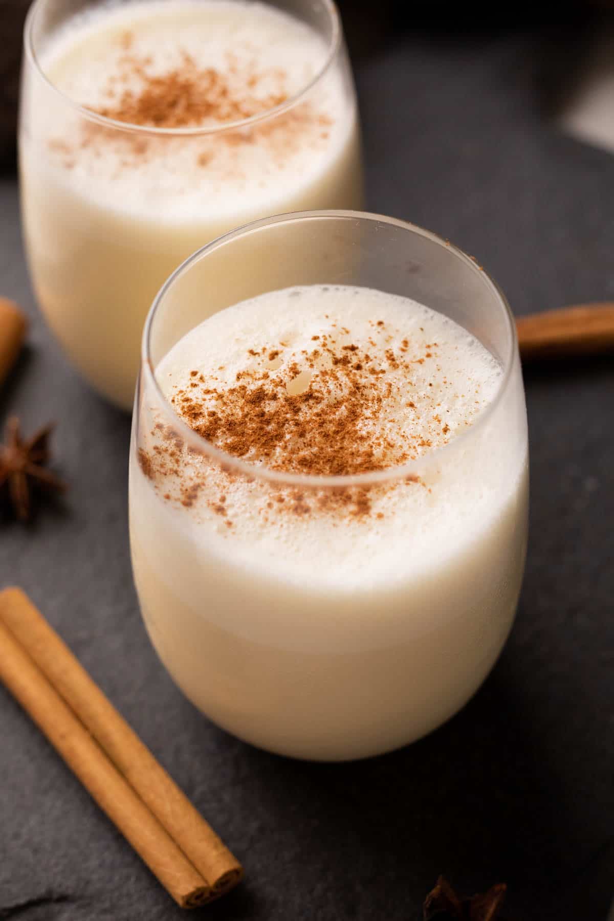 Picture of two glasses of non alcoholic eggnog with powdered cinnamon sprinkled on it