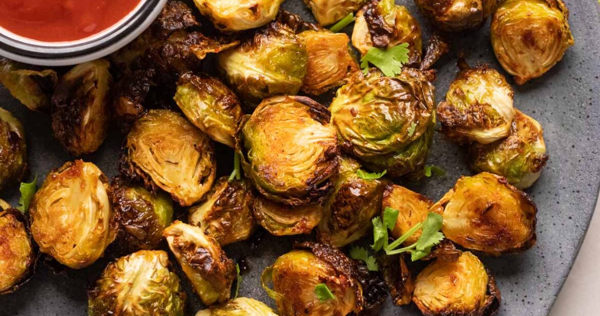 Roasted air fryer brussel sprouts served on a grey plate with ketchup on the side