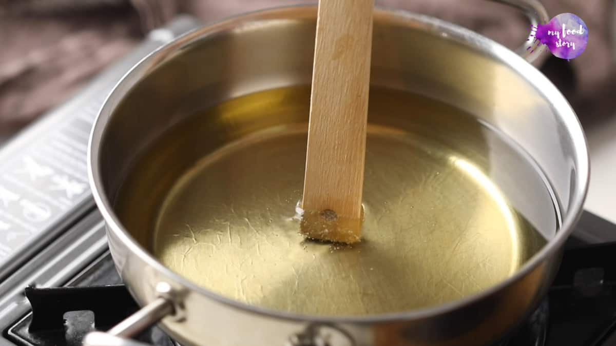 A ladle being dipped into a pan of hot oil