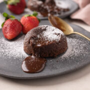 Picture of chocolate oozing out of mmocha lava cake with strawberries on the side