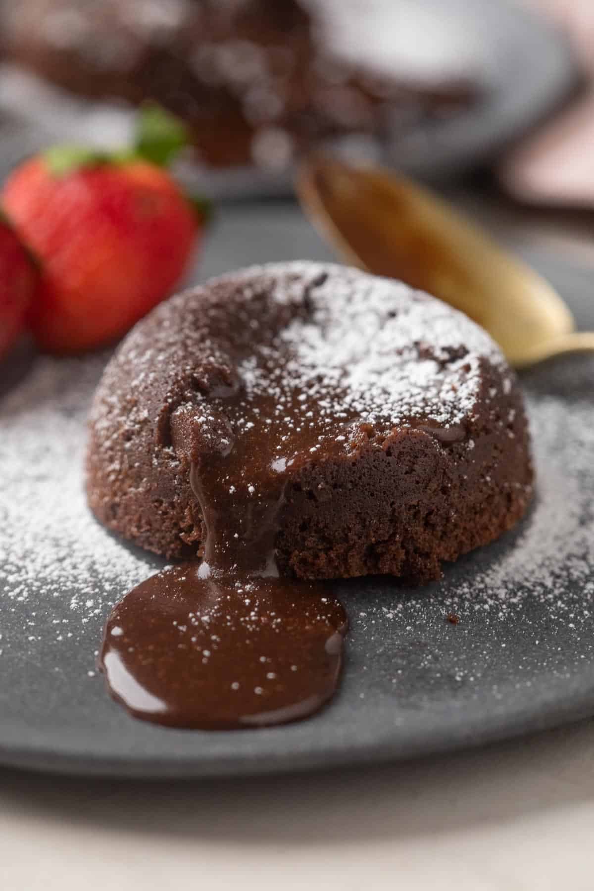 Picture of chocolate oozing out of mmocha lava cake with strawberries on the side