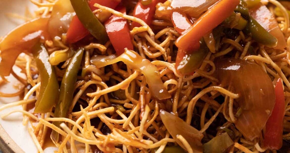 Aemrican Chopsuey served on crispy fried noodles in a white plate with a fork