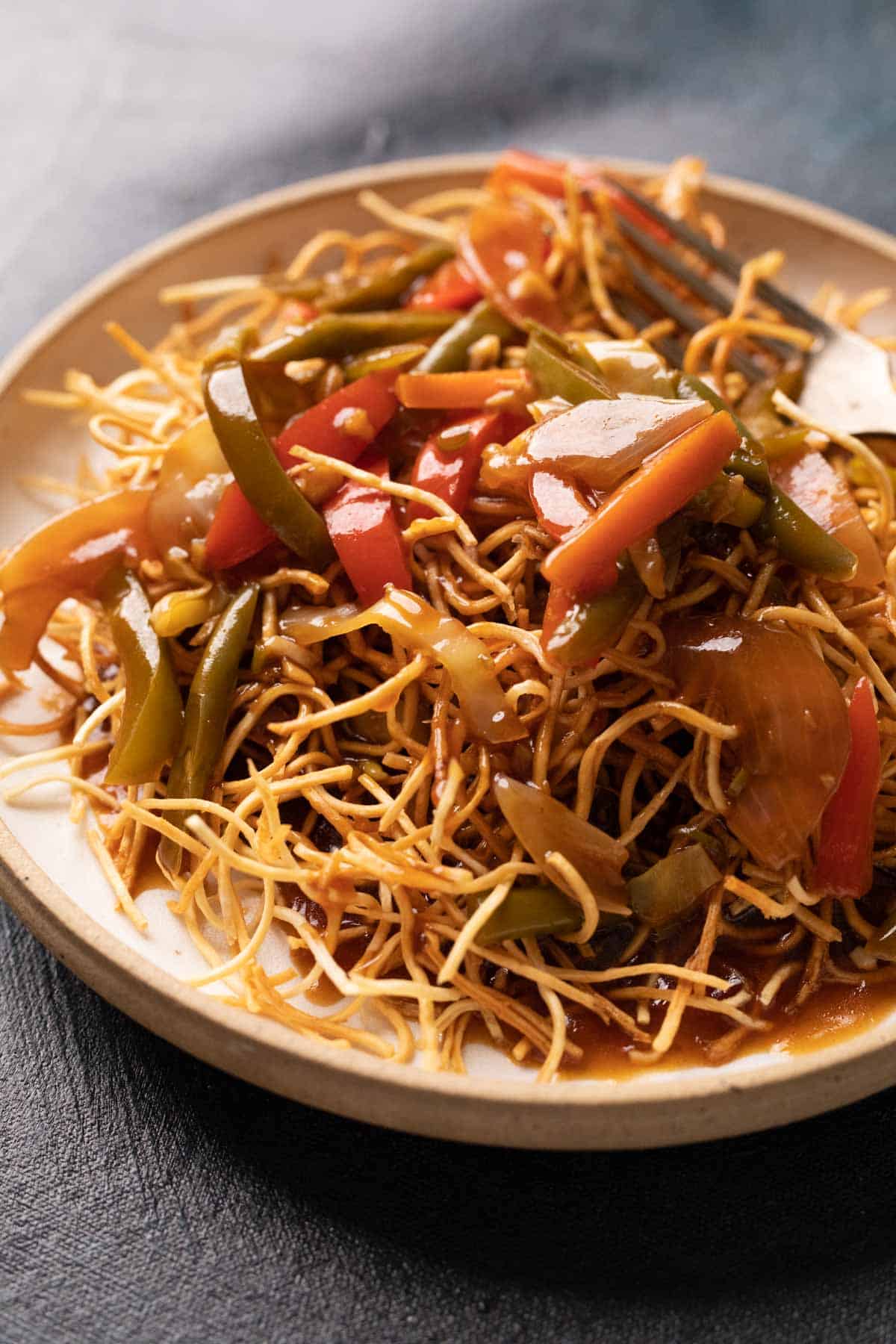 Aemrican Chopsuey served on crispy fried noodles in a white plate with a fork