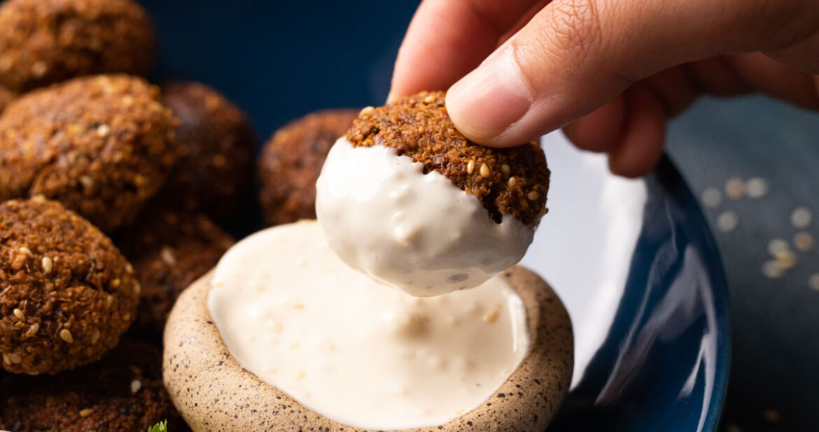 Picture of falafel dipped into tahini sauce