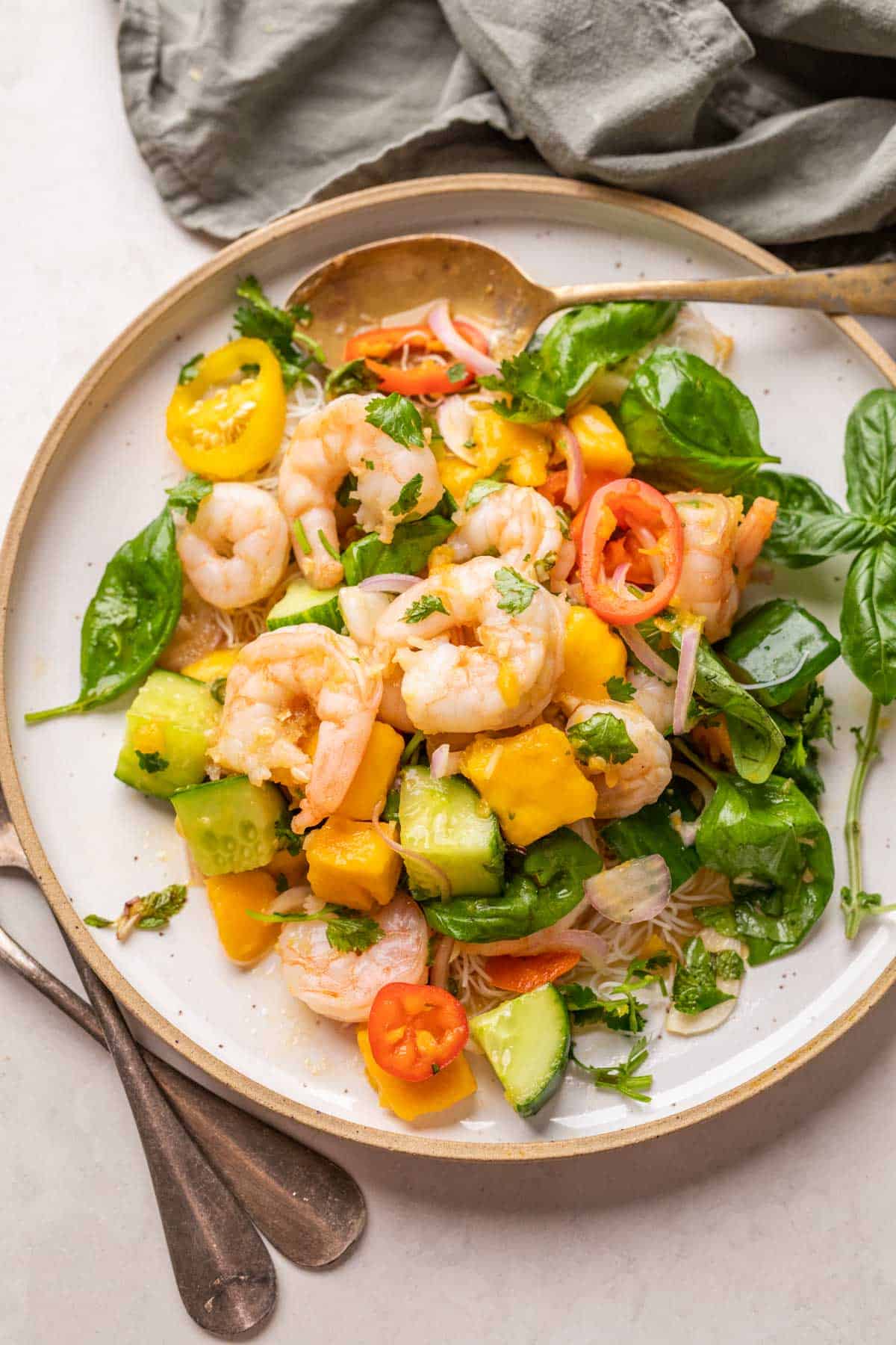 Thai Prawn Mango Salad served on a white plate with cutlery on the side