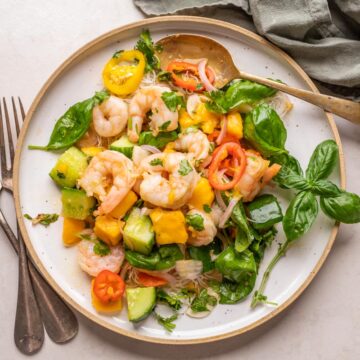 Thai Prawn Mango Salad served on a white plate with cutlery on the side
