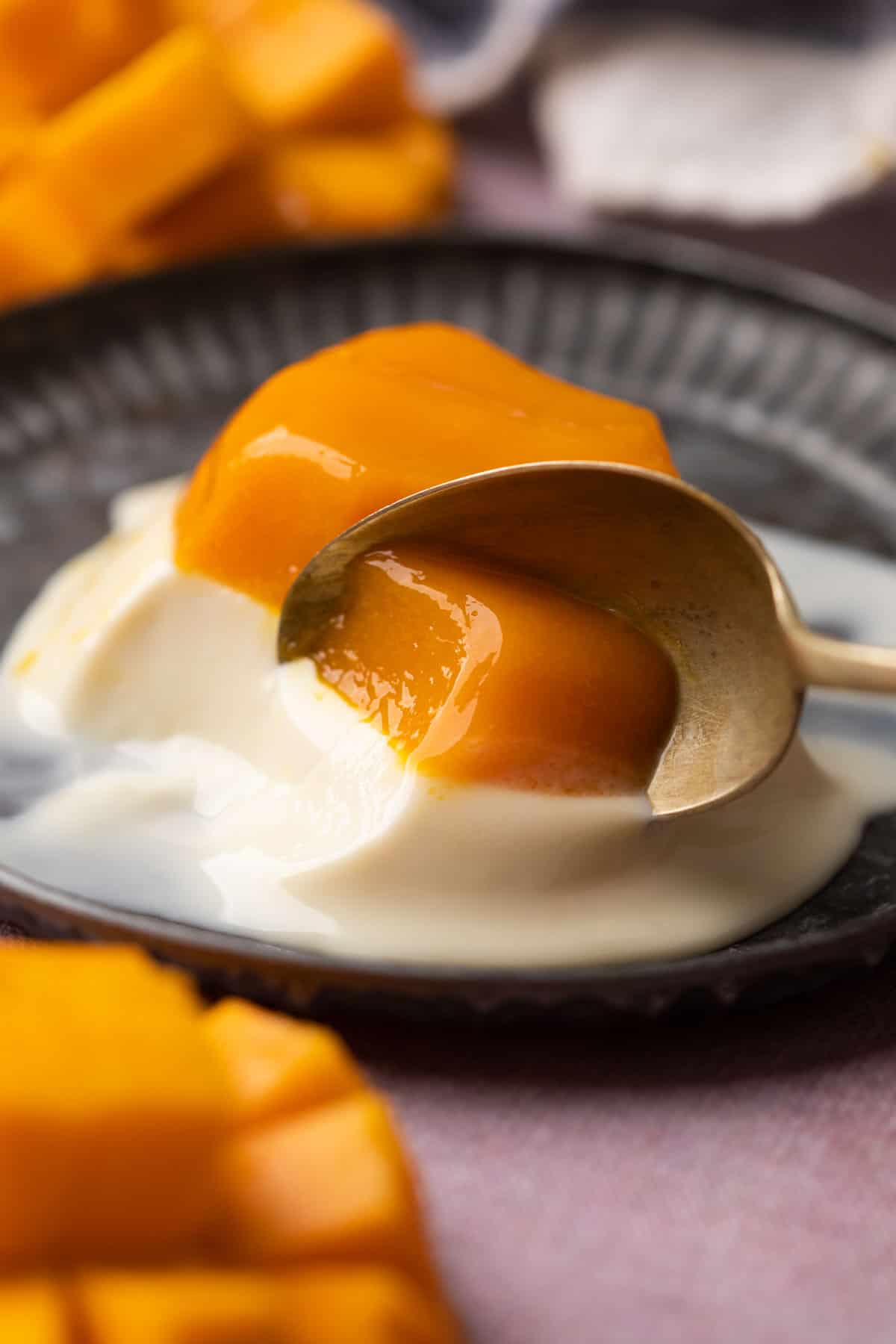 A spoon taking out a bite off the mango panna cotta