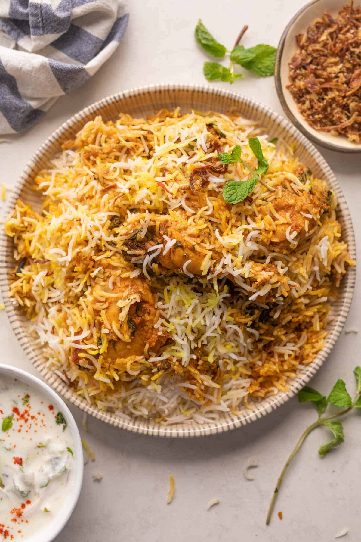 Chicken Biryani served on a plate with fried onions and raita on the side
