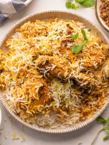 Chicken Biryani served on a plate with fried onions and raita on the side