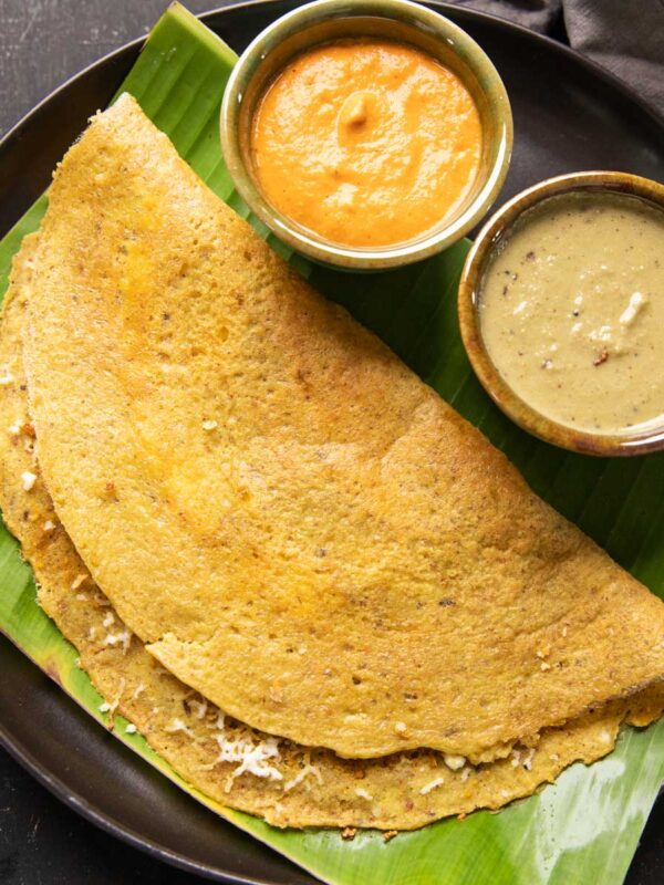 High Protein Dosa served on a banana leaf with chutney and curry on the side