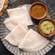 Neer Dosas served on a plate with chutney and curry